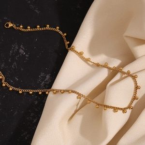 Detailed view of gold plated stainless steel bead chain with lobster clasp on satin fabric
