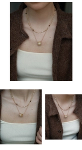 Detailed close-up of double-layer gold necklace with tiger eye beads and pavé diamond pendant