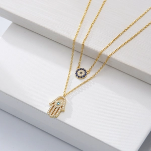 Detail of gold Hamsa hand and Evil Eye pendants with blue and white zircons