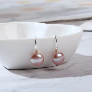 Macro view of pink pearl earrings on heart bowl with shimmering s925 silver hooks