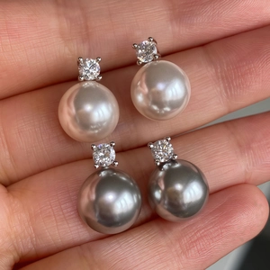 Hand holding white and gray natural freshwater pearl earrings with silver zircon studs