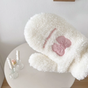 Detail of white plush mittens with pink bow embroidery and warm winter texture