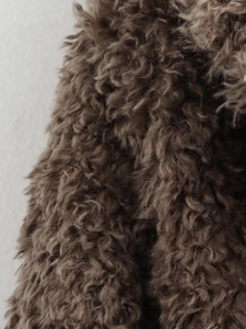Macro shot of deep brown curly faux fur texture showing soft and plush material detail