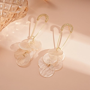 Detailed shot of golden safety pin earrings with sparkling rhinestones and pearl shell charms