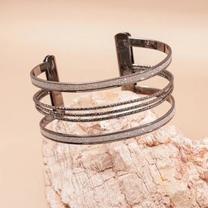 Detail of multilayer geometric open cuff bracelet in gunmetal grey on a stone display
