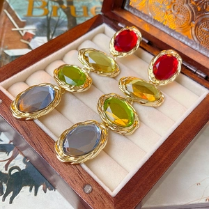 Close-up of vintage gold oval earrings with colorful gemstones in a wooden jewelry box
