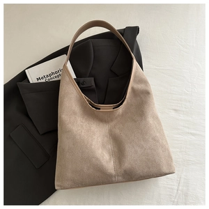 Detail of khaki suede tote bag with leather straps on a minimalist business aesthetic backdrop