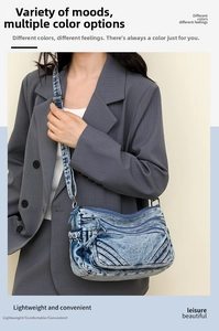 Detail of blue washed denim crossbody bag featuring multiple zippers and adjustable strap