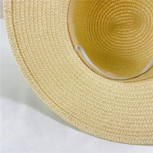 Detail of inner straw hat construction featuring beige sweatband and white elastic chin strap