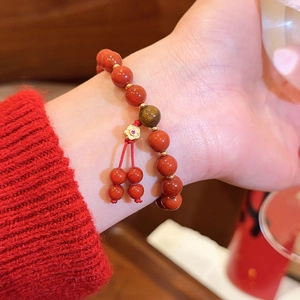 Detailansicht eines roten Achat-Perlenarmbands mit Tigeraugen-Perle am Handgelenk.