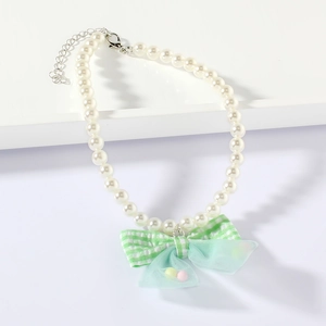 Detail of pet pearl necklace featuring a mint green mesh bow with colorful bead accents