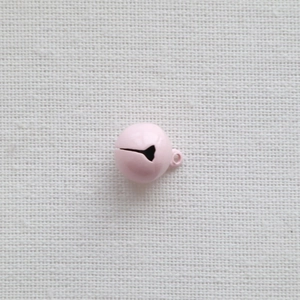 Detailed view of a 14mm pink metal bell with hanging loop on a natural linen background