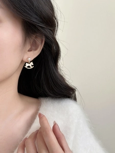 Close-up of elegant gold rocking horse earring with pearl and diamonds on a female model