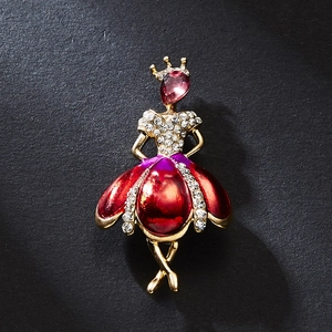 Detailed close-up of a golden ballerina brooch featuring pink gemstones and red accents