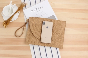 Pochette enveloppe en paille faite main sur bureau en bois avec accessoires chic