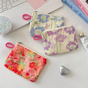 Overhead view of floral coin purses in blue, purple, and pink on a desk with accessories