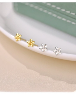 Macro shot of S999 sterling silver frangipani flower stud earrings in gold and silver