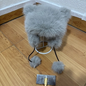 Detailed view of grey faux fur trapper hat with cute ears and plush pompom ties