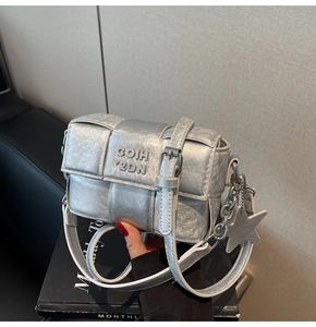 Détail du sac bandoulière argenté avec texture métallisée, pendentif étoile et logo lettres