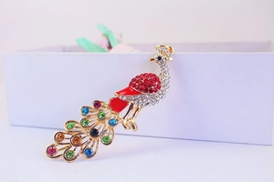 Detailed close-up of a golden peacock keychain featuring colorful crystals and red enamel