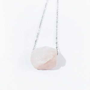 Macro shot of natural irregular raw pink crystal pendant on a silver-tone chain necklace