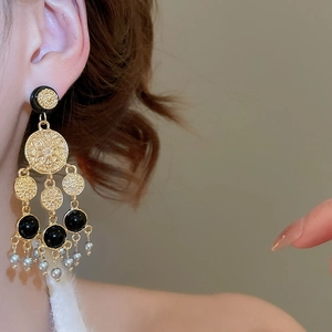 Vue détaillée de boucles d'oreilles rétro dorées avec détails noirs et perles grises