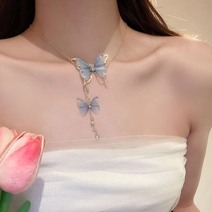 Detail of blue tulle butterfly pendant necklace with elegant gold tassel on a female model