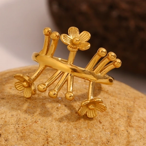 Macro d'une bague fleur en acier doré posée sur une roche texturée au style rustique