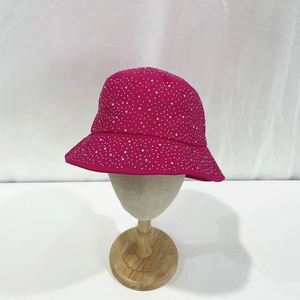 Detailed view of sparkly rhinestones on a rose red cotton bucket hat shown on a wooden head stand
