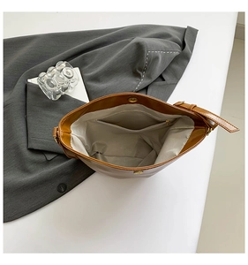 Detailed view of brown bucket bag interior featuring gray lining and zipper pocket