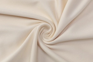 Gros plan sur la texture du tissu tricoté blanc crème avec des plis doux pour robe