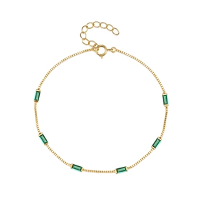Detailed close-up of a gold box chain bracelet featuring a green rectangular gemstone