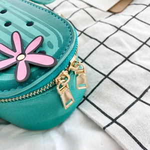Detail of teal crossbody bag with pink flower applique and golden zipper hardware