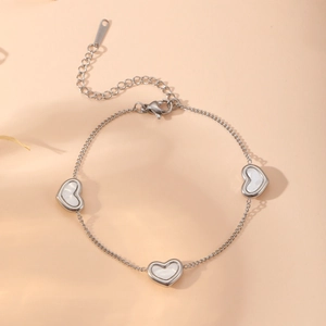 Bracelet en acier inoxydable poli avec breloques cœurs et inserts en nacre blanche