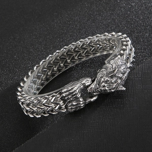 Detailed view of Viking wolf head clasps on a thick stainless steel braided chain bracelet
