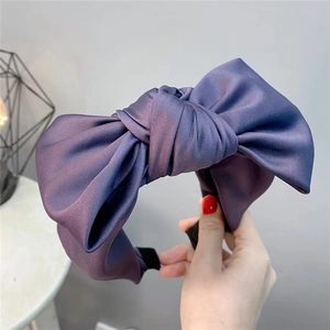 Detail of purple satin oversized bow headband with smooth silky texture and wide band