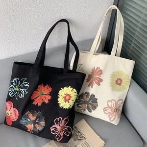 Detail of floral canvas tote bags in black and beige on a grey sofa with window light