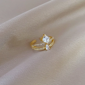 Macro detail of gold crown ring with square and teardrop stones on champagne satin