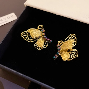 Detail of golden butterfly stud earrings with purple beads in a velvet jewelry box