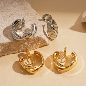 Polished gold and silver coiled clip-on earrings on a natural stone background