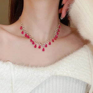 Close-up of a rose gold necklace featuring red teardrop stones and shimmering rhinestones