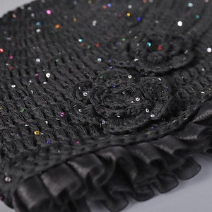 Detail of black crochet hat with handmade flowers, colorful sequins and satin ruffles