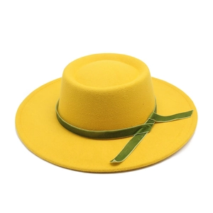 Detail of forest green velvet ribbon and cross knot on yellow wool felt fedora hat