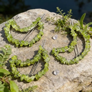 Three crescent moon hair clips with natural green crystal stones on a mossy rock