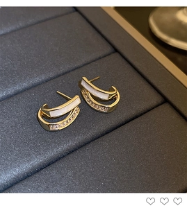 Detail of C-shaped double-layer gold earrings with white inlay and sparkling crystals