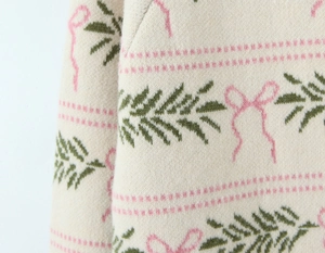 Close-up of knit fabric showing pink bow jacquard and soft wool texture detail