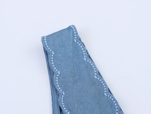 Vue macro d'un tissu bleu avec des bordures brodées ondulées et des détails texturés