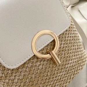 Close-up of straw woven texture with white leather flap and golden ring metal buckle