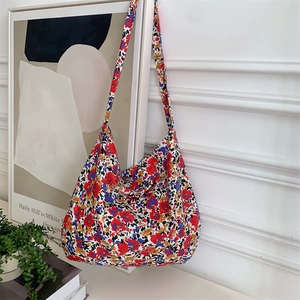 Detail shot of a floral tote bag featuring red and blue patterns on a textured fabric