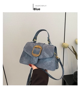 Detail of blue denim shoulder bag featuring a large decorative gold square buckle